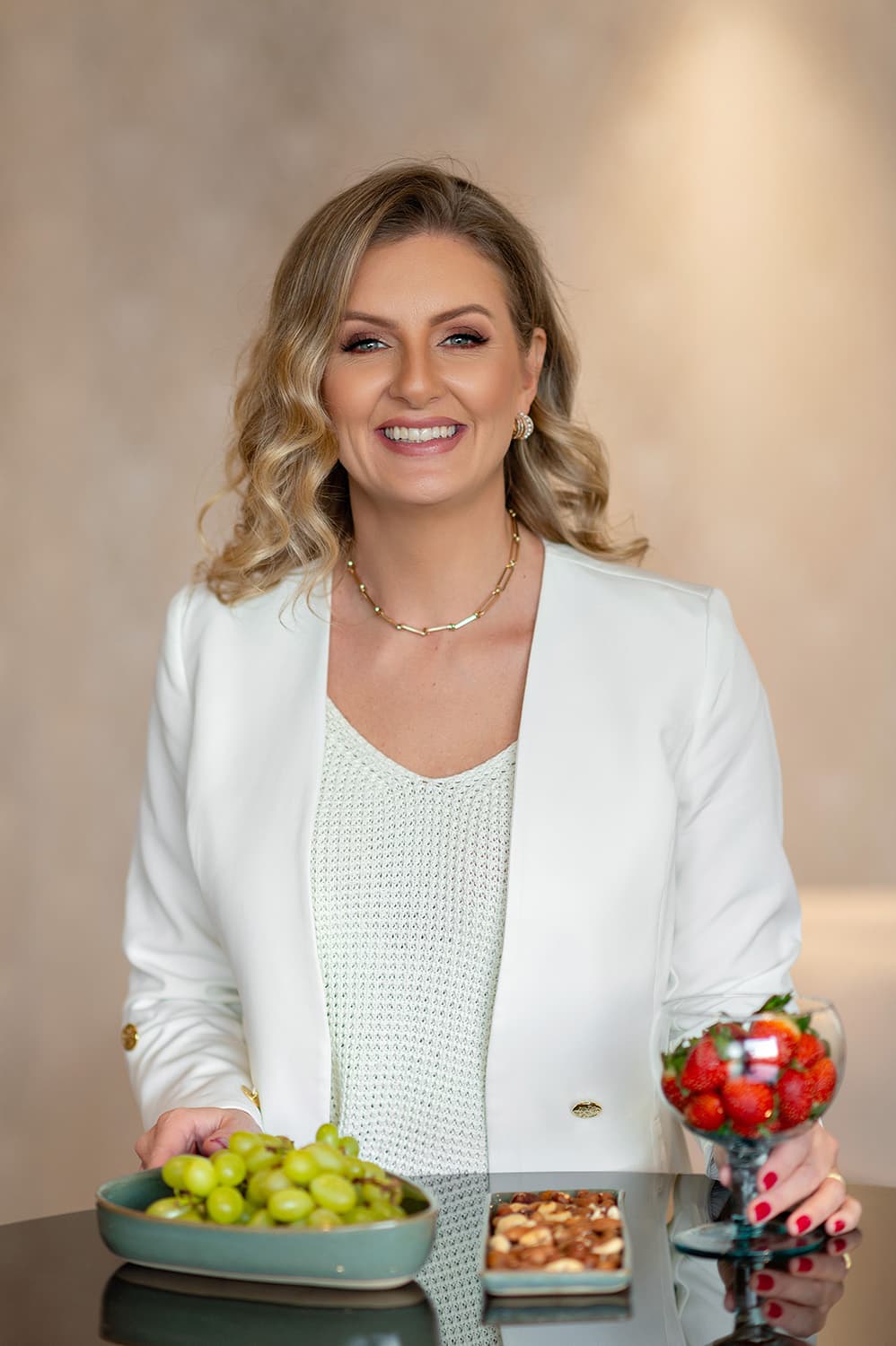 Andrea Bonfim, nutricionista, sorrindo enquanto prepara um prato com frutas e castanhas